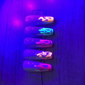 Glow-in-the-dark flame pattern nail stickers with neon fluorescent effect on wood base