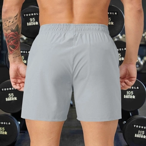 Rear view of grey men's athletic shorts with elastic waistband in gym setting