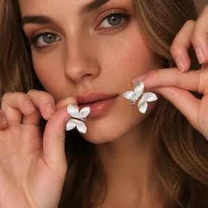 Close-up of white butterfly-shaped earrings with a pearlescent finish on model