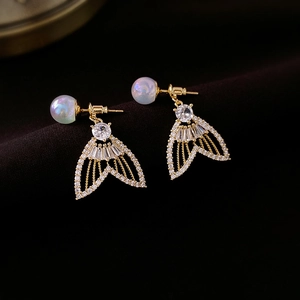 Détail de boucles d'oreilles queue de poisson avec zircons blancs et perles sur tissu