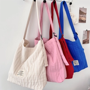 Detail of minimalist striped pleated canvas bags in cream, pink, red, and blue colors