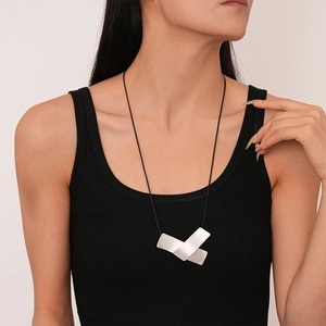Minimalist irregular geometric silver pendant on black cord shown on female model