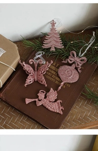 Pink glitter Christmas tree ornaments set on a vintage book with warm lights
