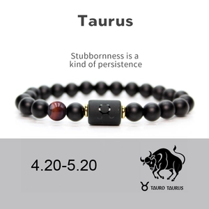 Detail of matte black Taurus zodiac bracelet with tiger eye stone and gold spacers