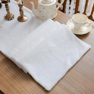 White faux fur table runner on a wooden dining table with a winter holiday aesthetic