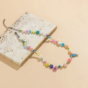Close-up of colorful daisy bead necklace with imitation pearls on a stone slab