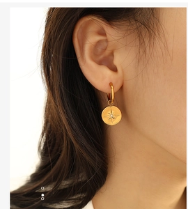 Close-up of model wearing golden round starburst earring with sparkling center stone
