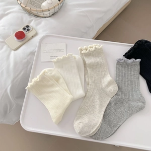 Detailed view of ruffle cuff knit mid-calf socks in various colors on a tray
