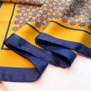 Detail shot of the yellow silk scarf featuring vintage geometric patterns and navy borders