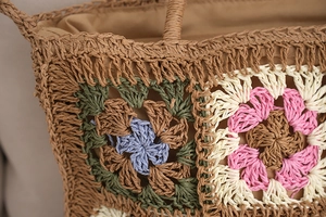 Close-up of colorful crochet flower patterns and woven texture on a straw beach bag