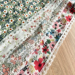 Detail of floral printed fabric with small daisy patterns and delicate white lace edges