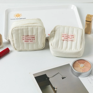 Detailansicht der cremefarbenen gesteppten Mini-Make-up-Tasche mit Reißverschluss