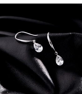 Vue macro de boucles d'oreilles goutte en zircone sur fond de soie noire texturée