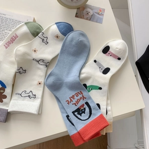 Flat lay of cotton socks with cartoon dog and floral patterns on a creamy desk