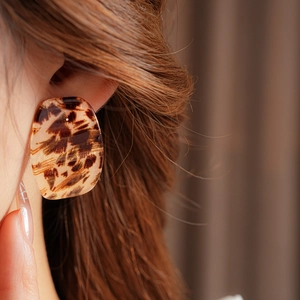 Close-up of leopard print square resin stud earring on model for vintage style