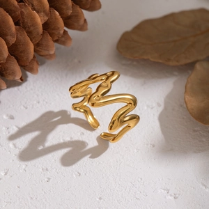 Bague ouverte dorée ondulée irrégulière sur fond blanc texturé avec décor d'automne