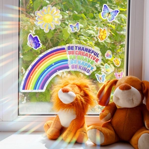 Rainbow and butterfly window stickers with motivational text on sunlit glass