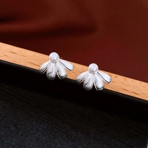 Macro shot of silver flower petal earrings with white pearl inlay on a black display box