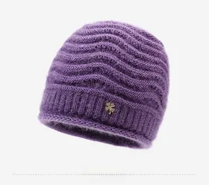 Dettaglio del cappello in maglia viola con texture soffice e spilla a quadrifoglio