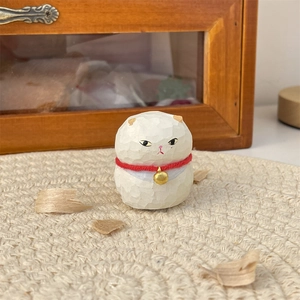 Macro view of hand-carved white cat figurine with red collar and bell