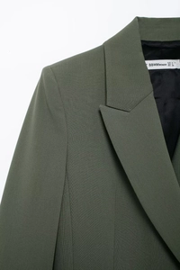 Détail de l'épaule et du col d'un blazer vert avec étiquette de marque et de taille