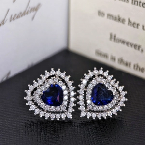Macro shot of heart earrings with blue crystal center and double zircon halo on leather