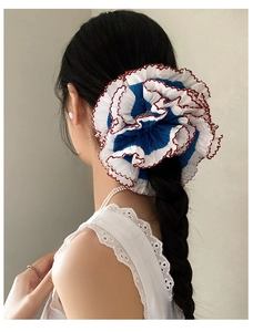 Close-up of oversized blue lace scrunchie with red wavy stitching on a ponytail