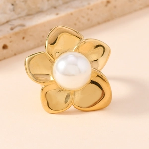 Minimalist golden stainless steel flower ring with pearl center on marble background