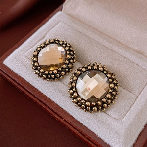 Macro shot of vintage style gold stud earrings with amber crystal center in a jewelry box