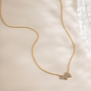 Gros plan d'un collier pendentif chien doré serti de pierres blanches et chaîne maille