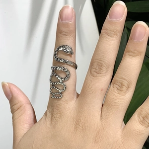 Bague serpent argentée exagérée en acier inoxydable portée sur un fond de feuilles vertes