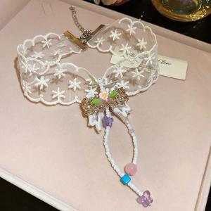 Detailed macro of white lace choker with bow, pastel beads and butterfly pendant