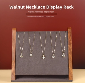 Detail of walnut wood necklace display with grey velvet fabric and golden pendants