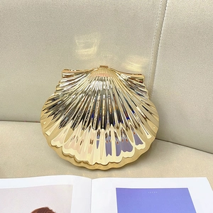 Pochette de soirée chic en forme de coquillage doré avec finition miroir sur fond beige chaud