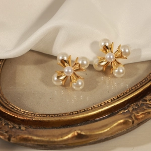 French vintage gold cross pearl stud earrings displayed on elegant silk background