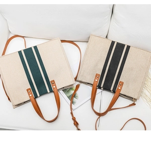Detail of striped canvas tote bags with brown leather handles on a white sofa