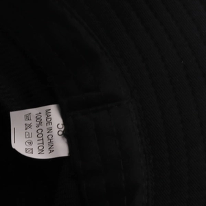 Dettaglio interno di un cappello pescatore in cotone nero con etichetta 100% cotone e simboli