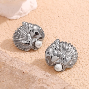 Macro shot of silver seashell and starfish earrings with pearls on a stone base