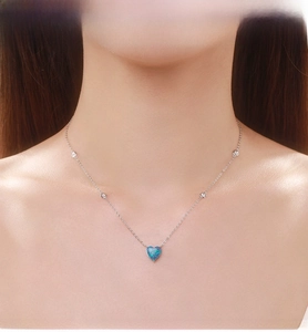 Macro shot of silver heart-shaped opal necklace with zircon accents on female neck