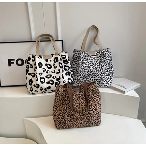 Détail de cabas en toile à imprimé léopard avec poignées en cuir sur présentoir épuré