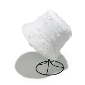 White cotton frayed bucket hat with fringe details on a metal stand for summer