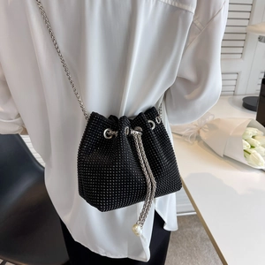 Fashionable black bucket bag with sparkling rhinestones and elegant chain strap on model