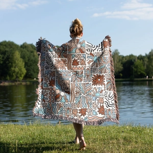 Detail of woven cotton picnic blanket with fringes and artistic sun shine pattern