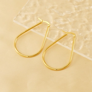 Polished gold stainless steel teardrop hoop earrings on water ripple texture background
