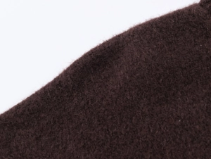 Macro close-up showing texture of thick dark brown warm knit fabric and plush fiber finish