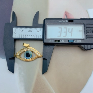 Detailed measurement of golden evil eye heart pendant showing 33.4mm width on digital caliper