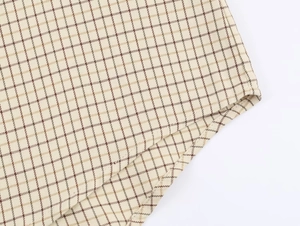 Detailed macro view of classic beige and brown plaid fabric texture and hem stitching