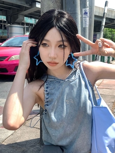 Street style shot of model wearing blue star-shaped acrylic earrings with denim outfit