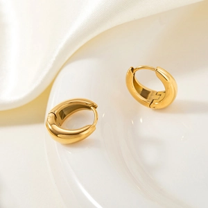 Polished 18k gold plated stainless steel huggie earrings on a white silk background