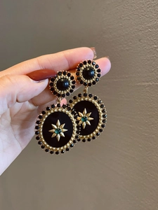 Macro shot of vintage resin flower earrings with gold sunburst star and green gem details